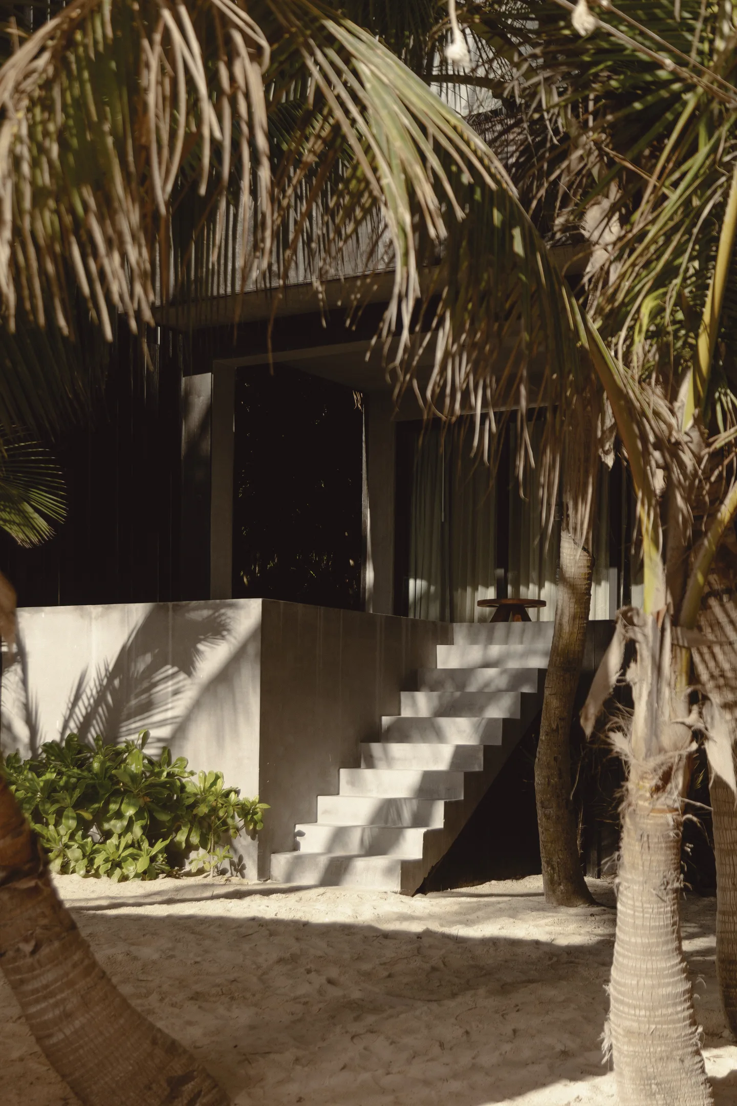 A beach house with a staircase leading to the entrance.