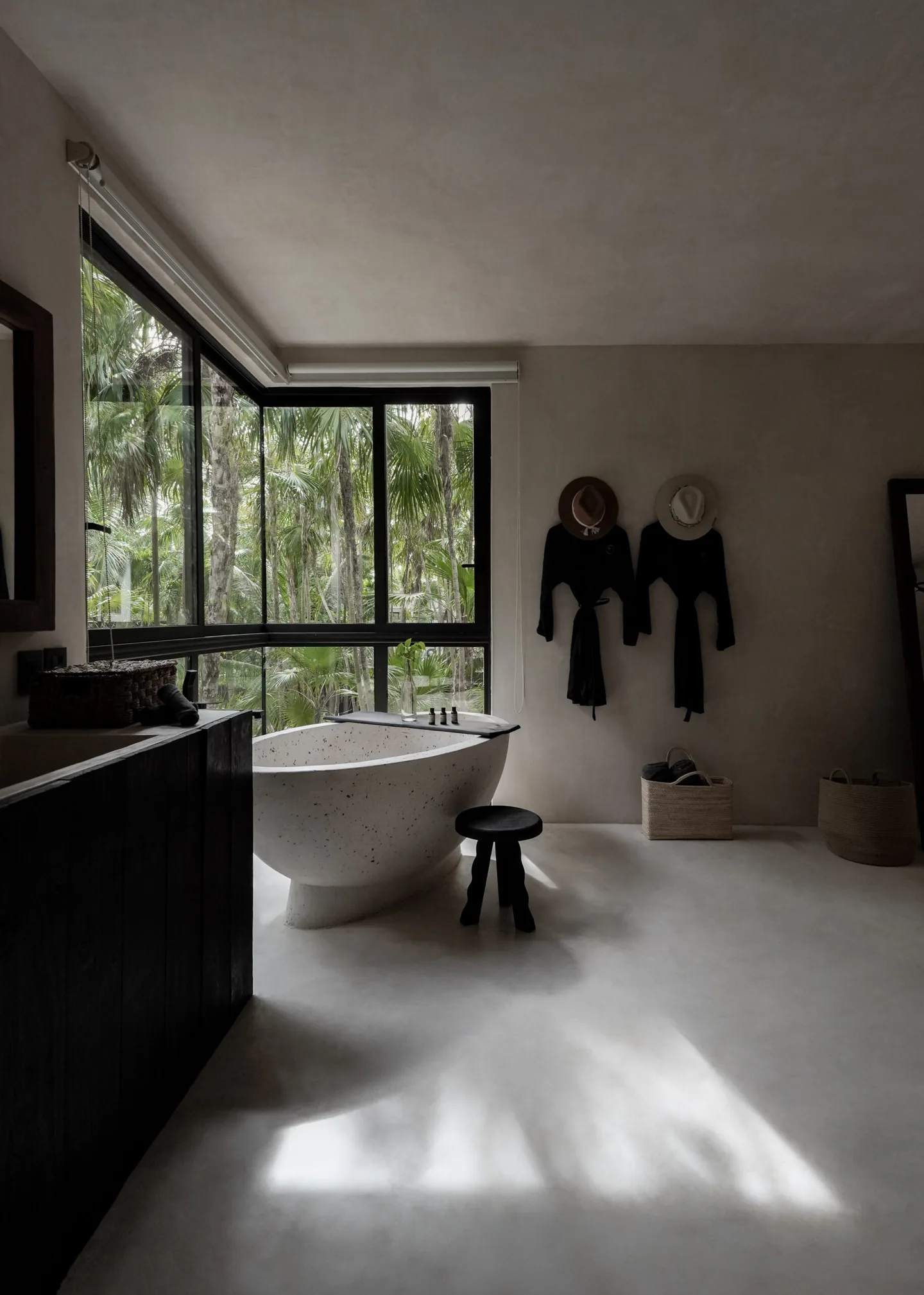 Bathroom with a bathtub, window, and tropical trees outside.
