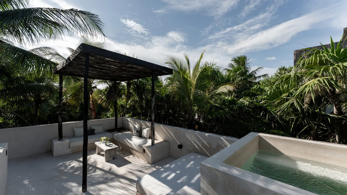 Outdoor patio with a lounge area and a hot tub under a canopy.