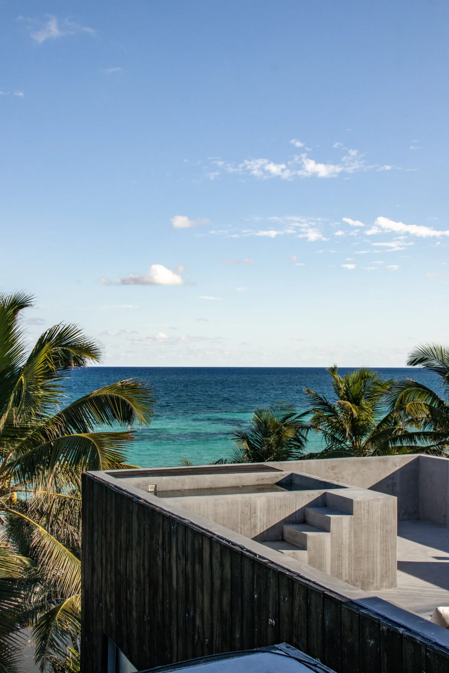 A modern building with a rooftop deck overlooking the ocean.