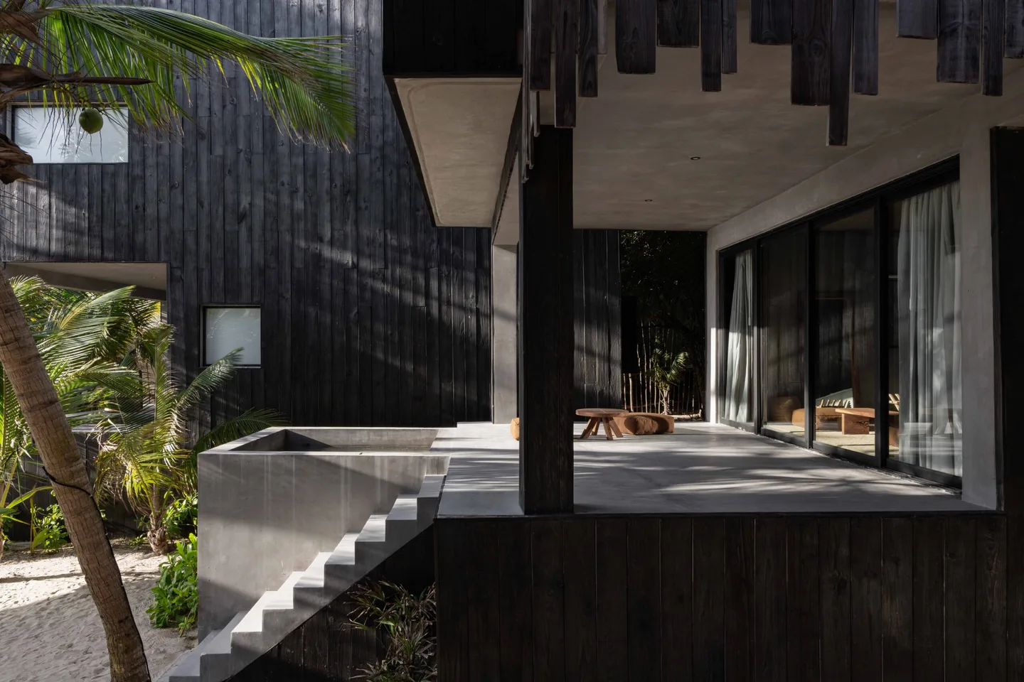 Modern beach house with black walls and gray concrete steps.