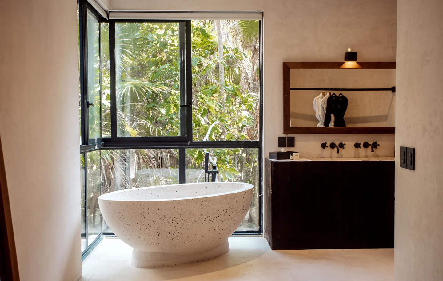 Bathroom with a bathtub, sink, and large window overlooking greenery.
