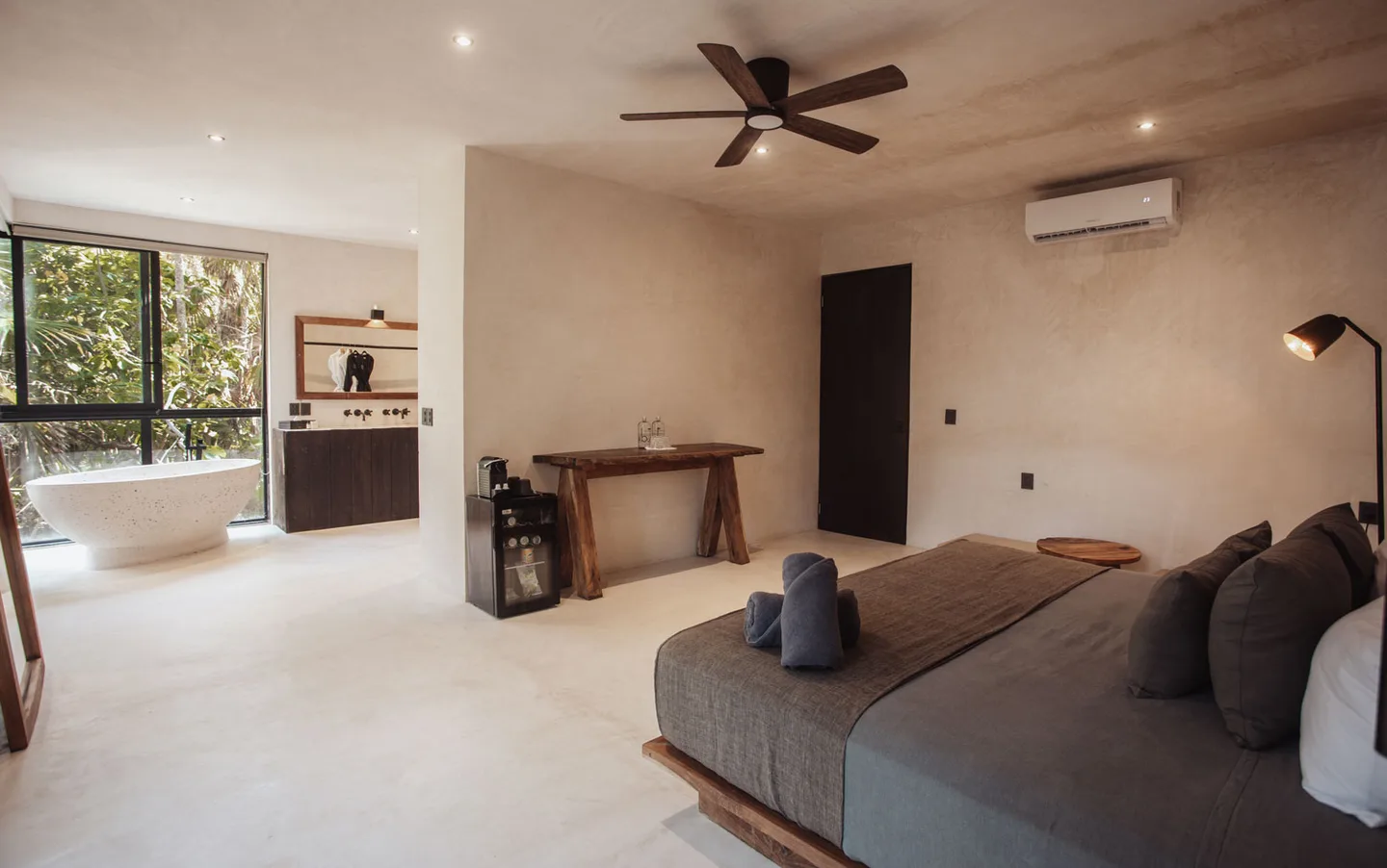 Bedroom with a bathtub, wooden desk, and a ceiling fan.