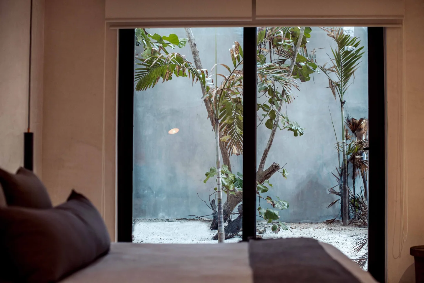 Bedroom with large glass windows overlooking a garden.