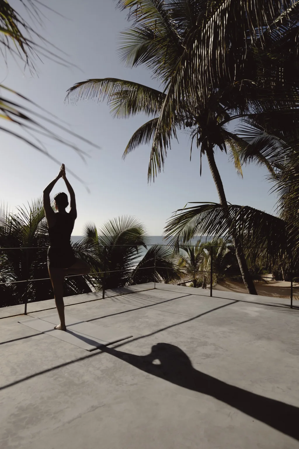 Una mujer practica yoga en una azotea con vista al mar.