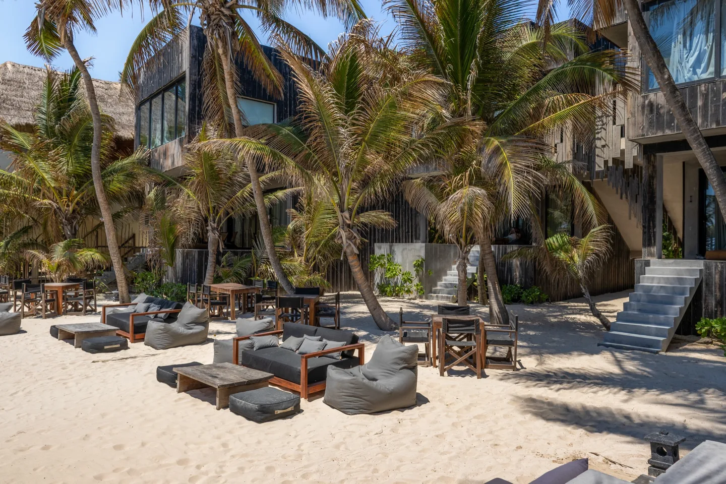 Beachfront seating area with lounge chairs and tables.